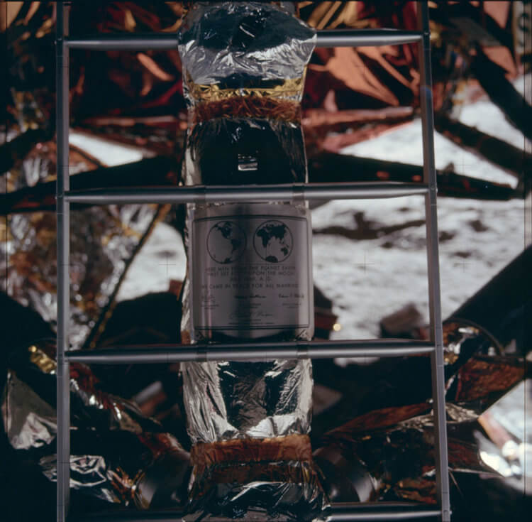 Первая высадка на Луну — «Аполлон-11». Памятная табличка: «На этом месте люди с планеты Земля впервые ступили на Луну в июле 1969 года нашей эры. Мы пришли с миром от имени всего человечества». Нижний блок посадочного модуля, на стойке которого была закреплена табличка, остался на Луне. Фото.