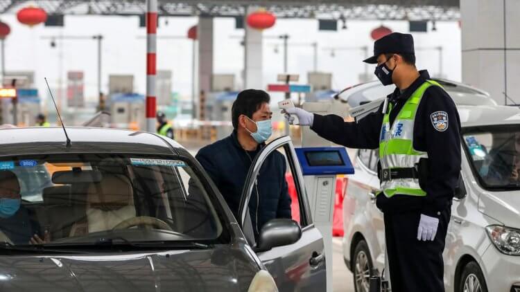 Что происходит в Китае и в мире прямо сейчас? Сотрудник ДПС измеряет температуру водителей в Ухани (Китай). Фото.