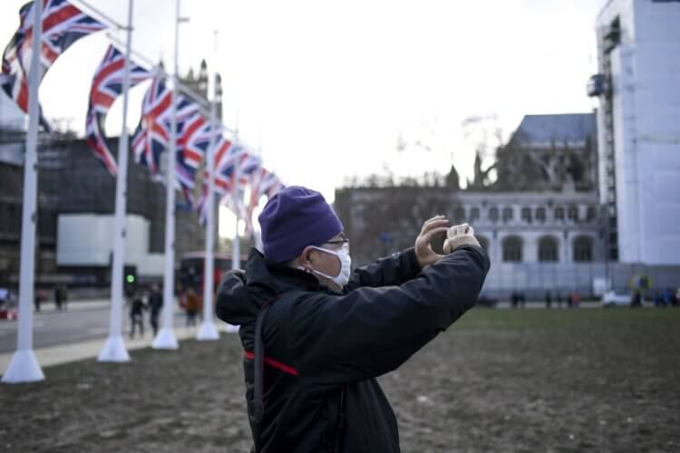 Похож ли CoVID-2019 на ОРВИ? Мужчина в маске делает снимок на Парламентской площади. Фото.