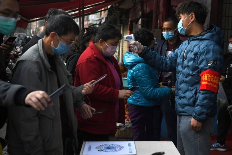 В Китае приложение решает, можно ли вам выйти из дома. Хотите так же? Люди получают QR-коды в своих телефонах, в то время как волонтеры проверяют их температуру перед тем, как пустить на рынок в Куньмине, в южной китайской провинции Юньнань. Фото.