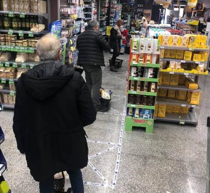 Правила поведения в магазине. В магазинах Италии, чтобы люди не подходили друг к другу слишком близко, на расстоянии нескольких метров друг от друга наклеены специальные метки. Фото.
