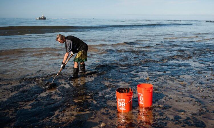 Как чистят разливы нефти. Рабочий убирает следы нефтепродуктов с береговой линии в Мексиканском заливе. Фото.