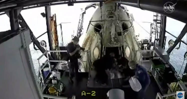 Корабль Crew Dragon успешно вернулся на Землю. Что ответит Роскосмос? Спасательная команда помогает астронавту Бобу Бенкену выйти из капсулы. Фото.