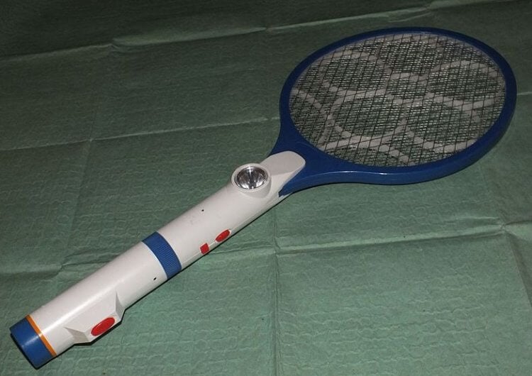 Мухобойка. В целом, все мухобойки отдаленно напоминают теннисную ракетку. На фото — электрическая мухобойка, которая поражает насекомых электрическим током. Фото.