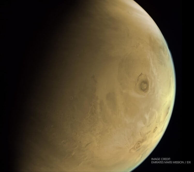 Самый большой вулкан в Солнечной системе. Видите темное пятно справа? Это марсианский вулкан Олимп. Фото.