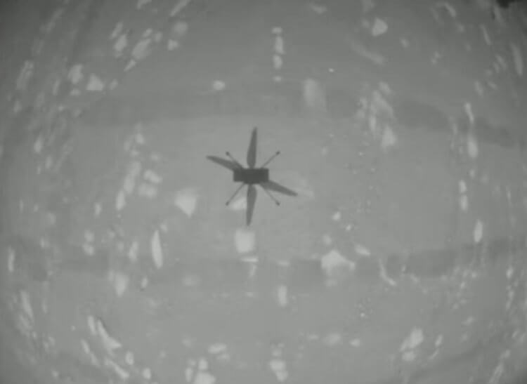 Первый полет марсианского вертолета Ingenuity. Тень взлетевшего вертолета Ingenuity, сфотографированная на встроенную камеру аппарата. Фото.