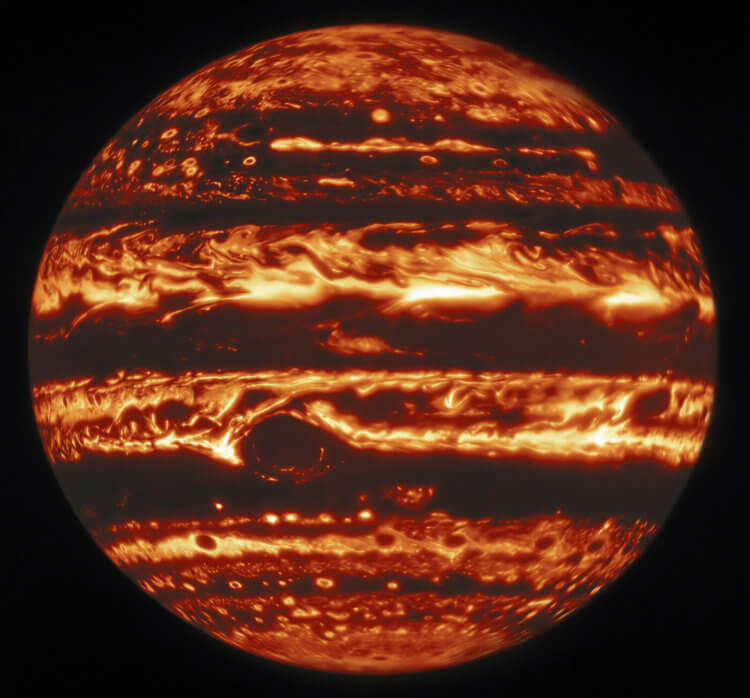 Новые фотографии Юпитера. Юпитер в инфракрасном свете. Вблизи вершины длинная коричневая особенность, называемая «коричневой баржей», простирается на 72 000 км в направлении восток-запад. Большое Красное пятно заметно выделяется в левом нижнем углу, в то время как меньший объект по прозвищу Красное пятно-младший появляется в правом нижнем углу. Фото.