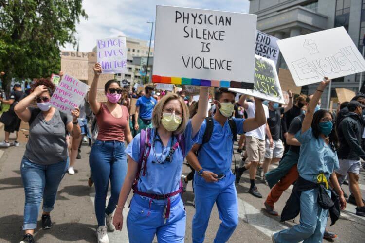 Отрицание науки. Антинаучные протесты в США. На фото девушка держит плакат с надписью «Молчание врачей – это насилие». Фото.