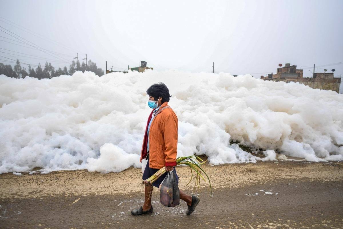 Экология Земли в 2022 году. Женщина на фоне пены в загрязненной реке. Фото.
