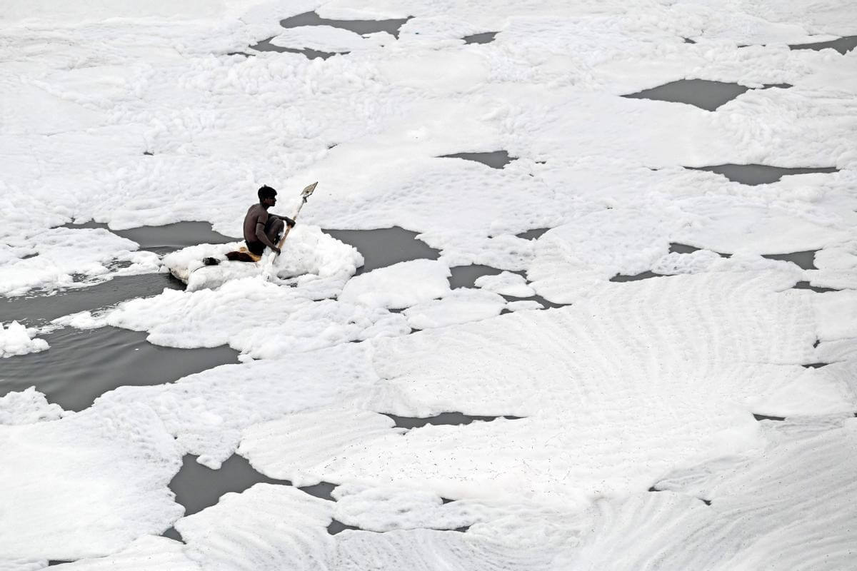 Экология Земли в 2022 году. Мужчина в загрязненной реке Индии. Фото.