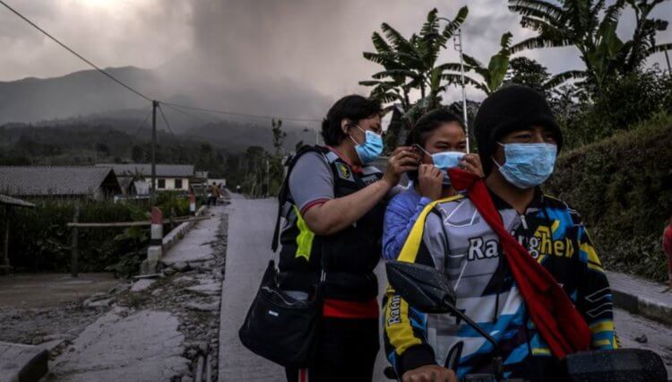 Извержение вулкана Мерапи в 2023 году. Полицейские раздают местным жителям маски, которые должны предотвратить попадание пепла в органы дыхания. Фото.