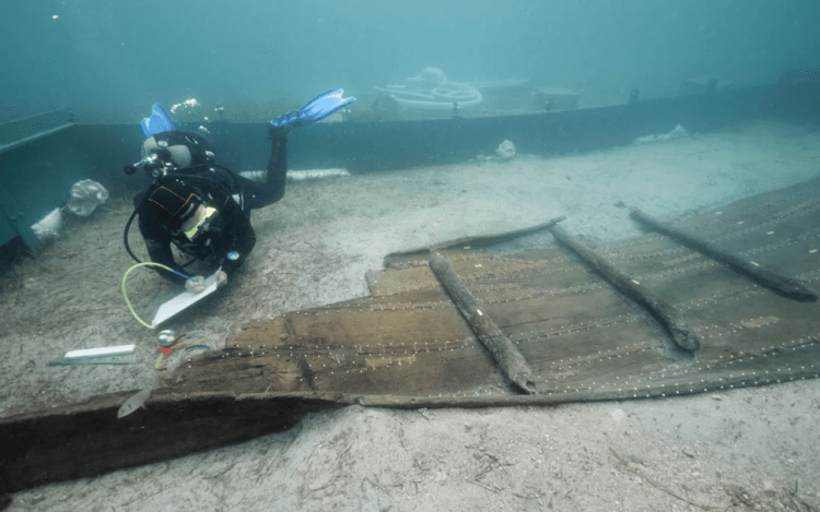 Древний корабль античных времен. Археологи достают на поверхность обломки древнего корабля. Фото.