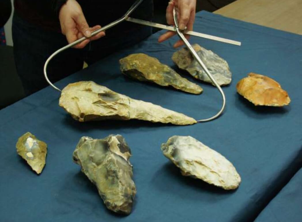 Загадочный образ жизни древних людей. Археолог измеряет длину топора при помощи специального инструмента. Фото.