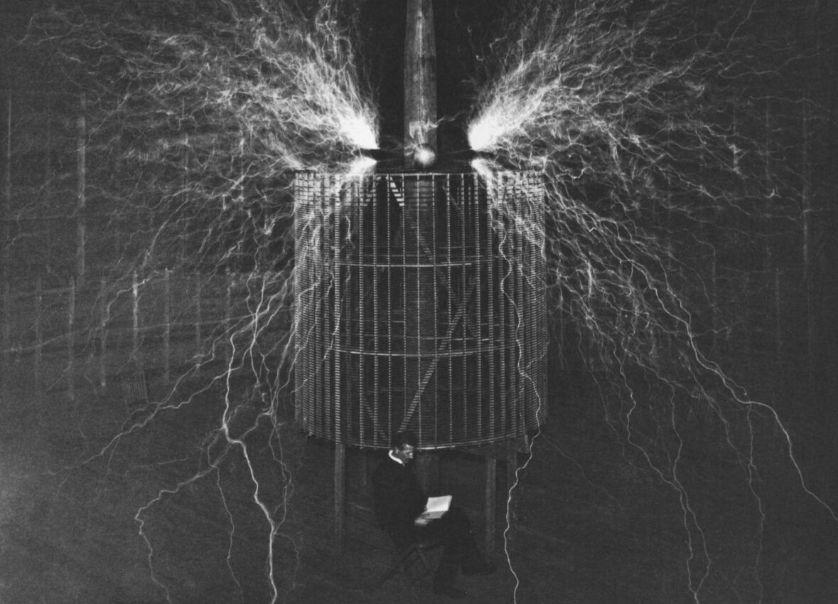 Фото Теслы среди молний. Никола Тесла читает книгу на фоне электрических разрядов. Источник изображения: Century. Фото.