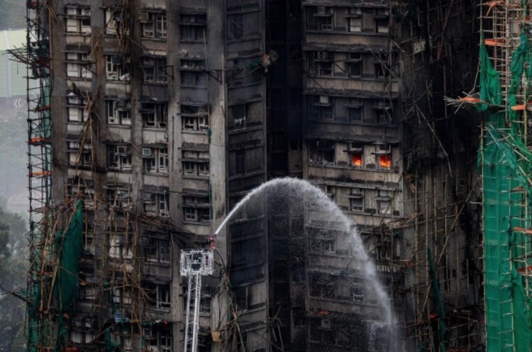 Пожар в Гонконге в 2025 году. На фотографии видно, как в некоторых квартирах до сих пор пылает огонь. Источник фотографии: LEUNG MAN HEI / EPA / ТАСС. Фото.