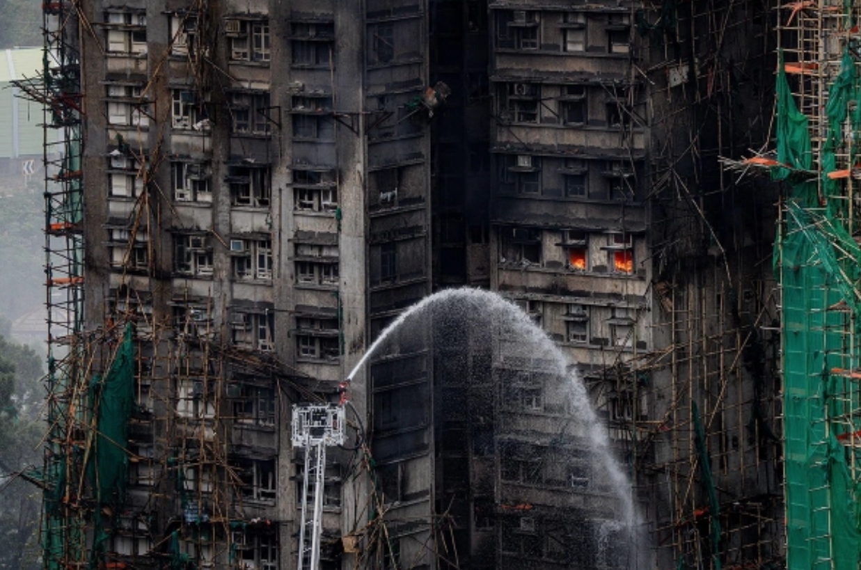 На фотографии видно, как в некоторых квартирах до сих пор пылает огонь. Источник фотографии: LEUNG MAN HEI / EPA / ТАСС. Фото.