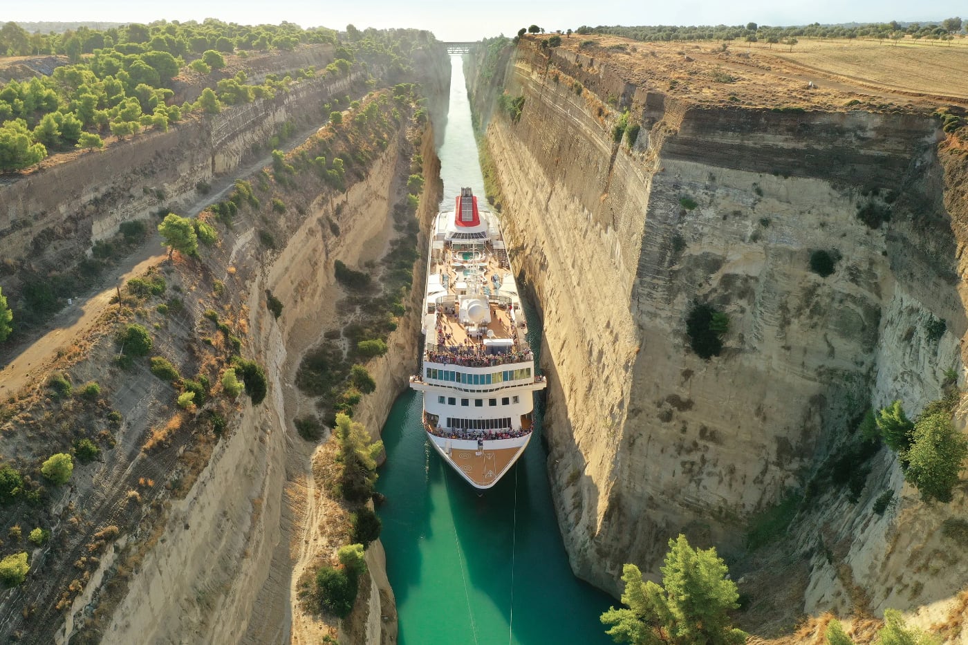 Почему Коринфский канал достроили только через 2500 лет. Буксиры проводят более крупные суда через узкий пролив. В 2019 году круизный лайнер M.S. Braemar стал самым большим судном, которое здесь проходило: с обеих сторон оставалось всего по 60 см свободного пространства. Источник изображения: iphones.ru. Фото.