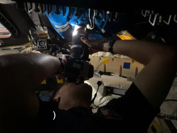 Астронавт Джереми Хансен делает снимок через кожух / шторку камеры, закрывающую иллюминатор № 2 космического корабля «Орион». Фото.