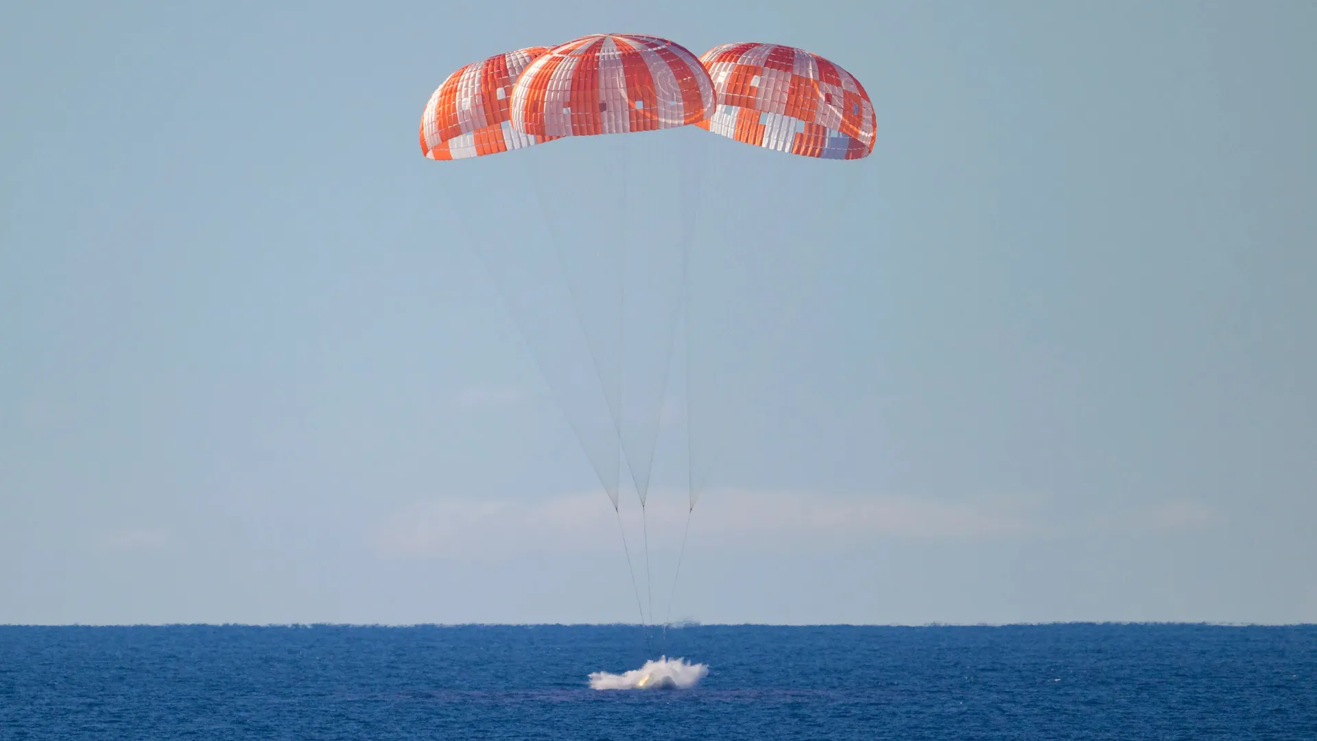 The Orion capsule splashes down in the Pacific Ocean after returning from the Moon